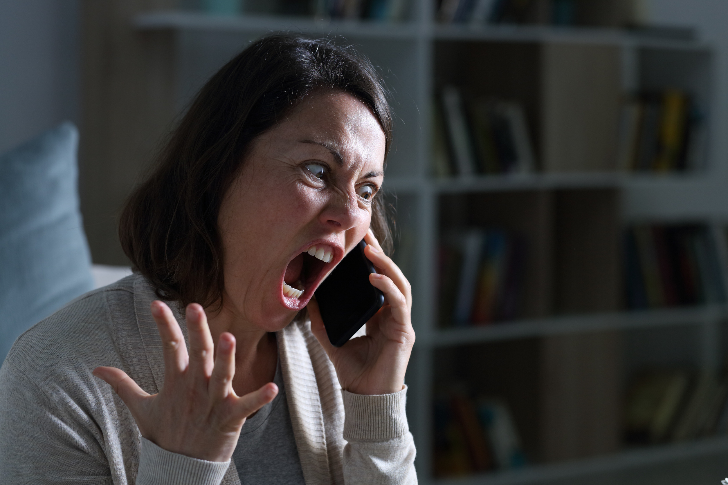 Angry adult woman screaming calling on smart phone