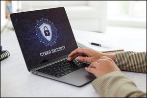 Person working on a laptop showing a cyber security shield and padlock.