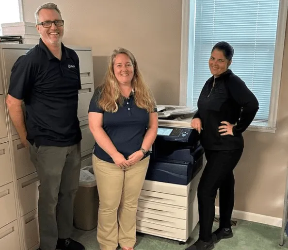 iTech technicians standing in front of a Xerox printer, showcasing advanced printing technology and expert service for modern business efficiency